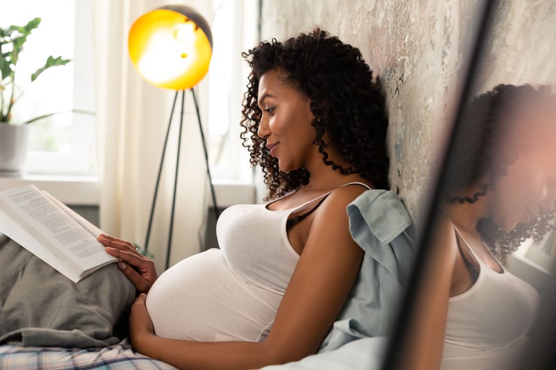 Pregnant woman reading a book in bed